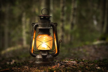 Vintage Old Lantern Lighting In The Dark Forest. Travel Camping Concept. Burning Lantern On A Moss At Forest In The Night.