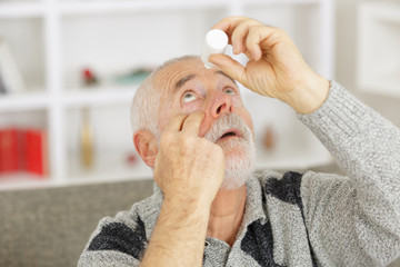 elderly person using eye drops