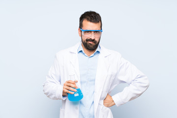 Wall Mural - Young scientific holding laboratory flask over isolated background angry