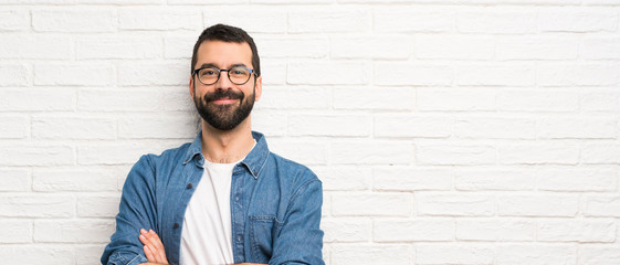 Poster - Handsome man with beard over white brick wall keeping the arms crossed in frontal position