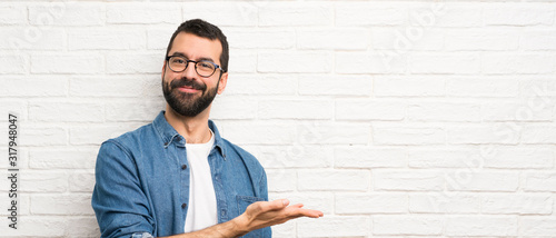 Fotografía Handsome man with beard over white brick wall presenting an idea while looking s