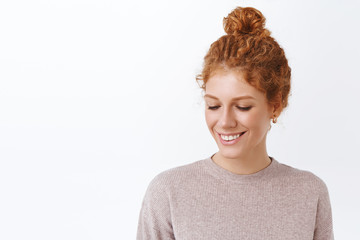 Lovely, attractive and tender redhead curly woman in stylish blouse, lookign down, blushing from compliment, standing happy and modest, smiling, laughing happily, standing white background