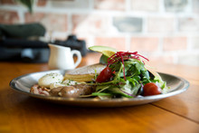 Close-Up Of Pancakes With Salad And Sausage Served In Plate On Wooden Table