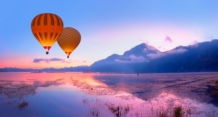 Fishing village on the coast of the Lake Batur on the background amazing sunset with hot air balloon - Bali island, Indonesia