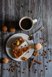 Fototapeta Uliczki - Cup of coffee and two slices of cake and macaroons on the plate on wooden table