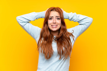 Wall Mural - teenager redhead girl over isolated yellow background frustrated and takes hands on head