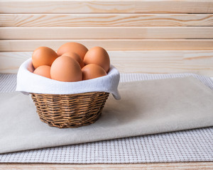 Brown fresh raw eggs lie on a white napkin in a small rough rustic basket