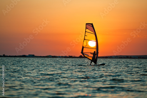 Plakaty Windsurfing  seascape-nieruchomej-powierzchni-morza-czlowiek-cwiczacy-windsurfing-i-zloty-zachod-slonca-na-niebie-w-lecie