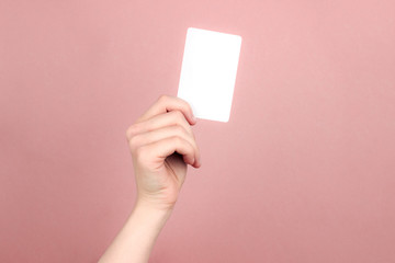 Female hand holding white business card on colorful pink background. Template, mockup, blank for web, social media, advertisement with copy space. Marketing, technology concept. Stock photo.
