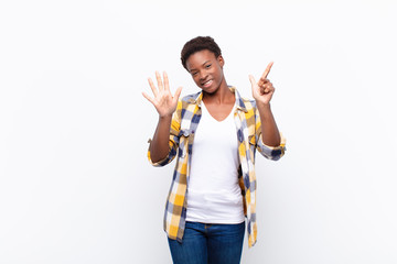 young pretty black womansmiling and looking friendly, showing number seven or seventh with hand forward, counting down