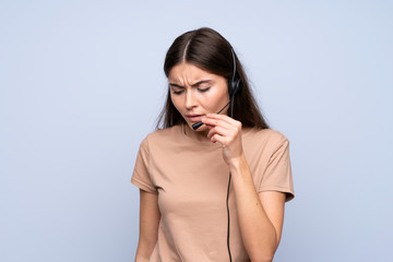 Wall Mural - Young woman over isolated blue background working with headset