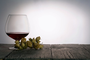 Glasses with red dry wine. A bouquet of dried roses. Stand on wooden boards. Shot in backlight.