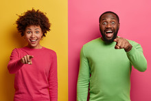 You Are What We Need. Positive Surprised Afro American Woman And Man Smile Broadly And Indicate Directly At Camera, Make Choice, Choose You With Happy Faces, Wear Bright Clothing. Colorful Image