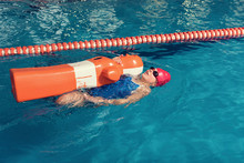 High Angle View Of Girl Swimming With Dummy In Pool