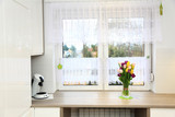 Fototapeta  - Klorowe tulipany w wazonie na parapecie białego wspłóczesnego okna w jasnej kuchni.