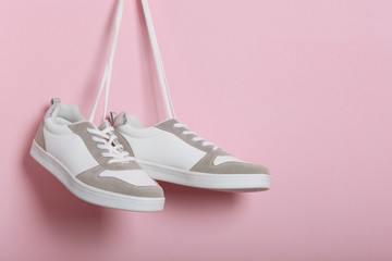 Wall Mural - Modern trendy sneakers hang on laces on a colored background. Casual shoes, sports shoes. Place to insert text.