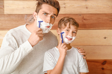 Poster - Father and his little son shaving against wooden background