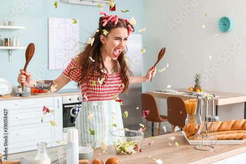 Fotomural Funny angry housewife cooking in kitchen