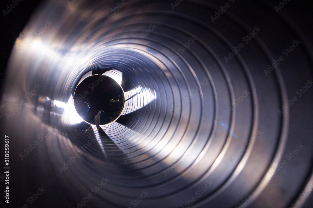 closeup view from inside the galvanized steel air duct on the exhaust fan in the background light, the front and back background is blurred with a bokeh effect - obrazy, fototapety, plakaty 
