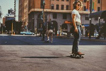 Woman Skateboarding On Street In City