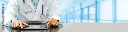 Fotomural Male doctor sitting at table with tablet computer in hospital office