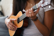 Close-up Of Latino Woman Holding Ukulele And Learning How To Play. Young Female Exercising In Playing. Musical Wooden Instrument. Music And Art Concept