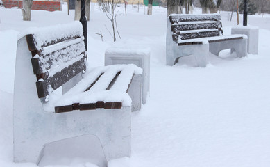 Two massive benches are covered with fresh snow in the winter Park.