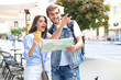 © ty - Beautiful young couple holding a map and smiling while standing outdoors.