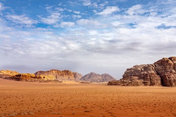 Wall Mural - Cliffs and caves on a desert full of dry grass under a cloudy sky during daytime