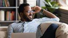 Happy African American Man Relaxing With Laptop Looking Away Dreaming