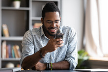 Happy African Man Using Smartphone Sit At Home Office Desk
