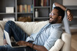 © fizkes - Relaxed african man resting on couch using laptop at home