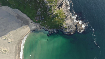 Wall Mural - Top view of the coast of a Norwegian island with a sandy beach, greenish water and a small mountain hill