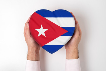 Wall Mural - Flag of Cuba on a heart shaped box in a male hands. White background