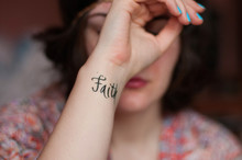 Close-Up Of Faith Text Tattoo On Woman Wrist