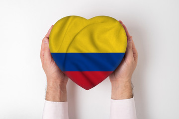 Wall Mural - Flag of Colombia on a heart shaped box in a male hands. White background