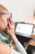 © astrosystem - Woman feeling unwell, headache while working on a laptop.