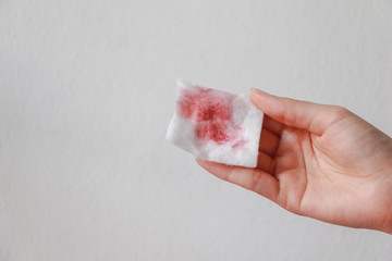 Wall Mural - asian woman holding dirty cotton pads with make up on white background. make up removing.