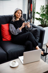 Wall Mural - Smiling mature woman at work with gadgets stock photo