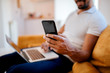 © bnenin - Using laptop and smartphone while sitting on the sofa. Close-up, focus on the foreground.