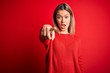 Young beautiful blonde woman wearing casual sweater over red isolated background pointing displeased and frustrated to the camera, angry and furious with you