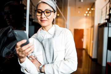 Wall Mural - Joyful boss with smartphone in office stock photo