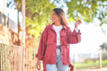 Canvas Print - Young beautiful woman wearing red jacket smiling happy and confident. Standing with smile on face at the town street