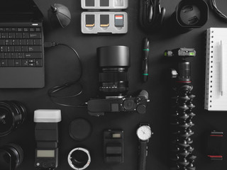 Wall Mural - top view of work space photographer with digital camera, flash, cleaning kit, memory card, tripod and camera accessory on black table background