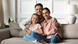 © fizkes - Portrait of happy young family with daughter relaxing on couch