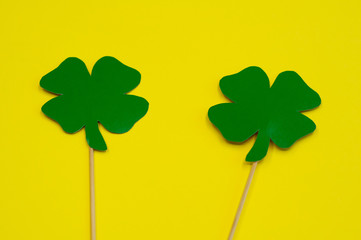 Happy Saint Patrick's of handmade paper clover leaves on stick on yellow background with copy space