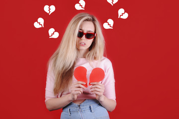 Young caucasian woman in sunglasses with broken red heart in hands. Valentine`s Day. Broken heart concept.