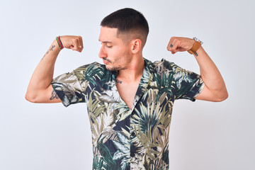 Wall Mural - Young handsome man wearing Hawaiian summer shirt over isolated background showing arms muscles smiling proud. Fitness concept.