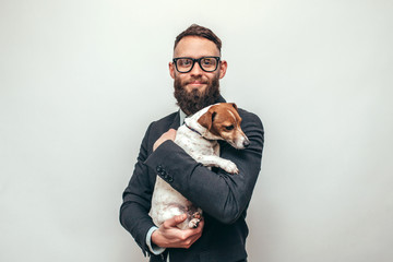 Handsome man with beard in formal suit hugs his cute dog Jack Russell Terrier isolate over white background. Animal lover. Friendship concept.