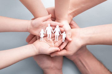 Family care concept. Hands with paper silhouette on table.